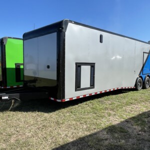 Rock Solid 8.5x36 race car trailer with triple torsion axles, escape door, electric awning, generator compartment, air conditioning, E-track flooring, and two-tone Silver Frost and True Blue polycore exterior for sale