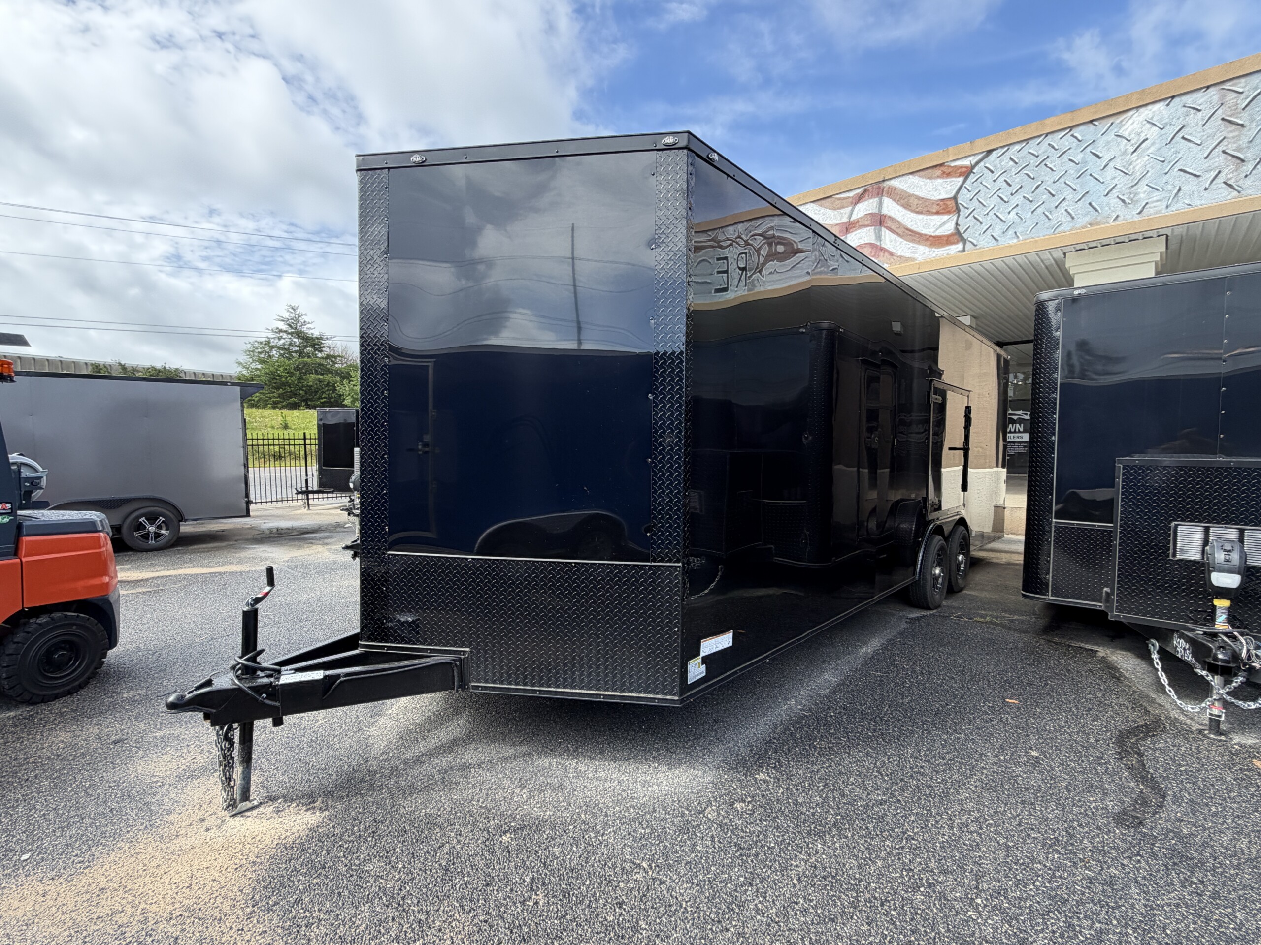 Deep South 8.5x24 triple axle enclosed car hauler trailer with black blackout package, alloy wheels, Polycore semi-screwless exterior, escape door, and 7'6" interior height.