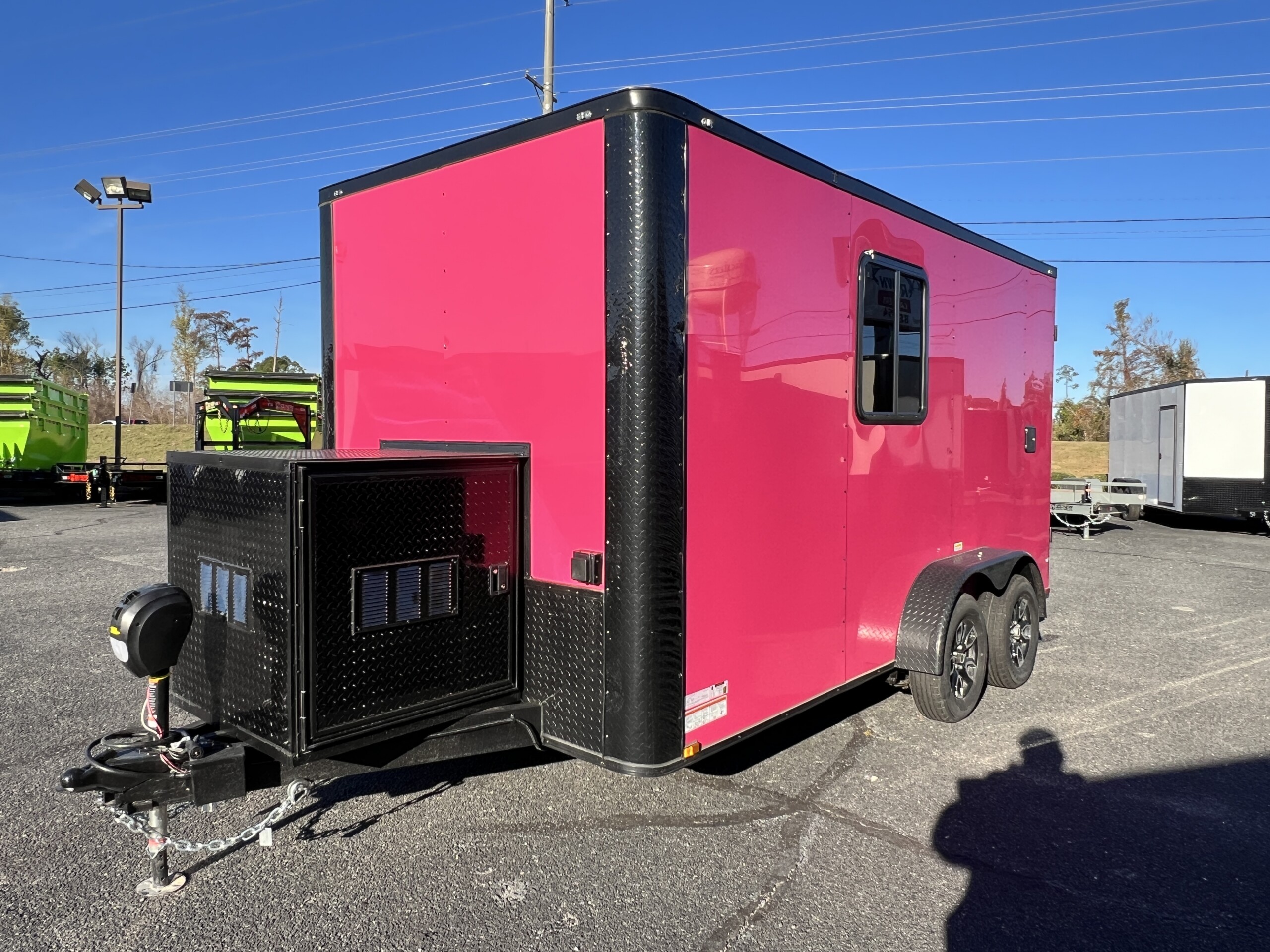 Pink Genesis Series 7x12 pet grooming trailer with blackout trim, Flying Pig tub, generator box, water tanks, cabinets, and air conditioning.