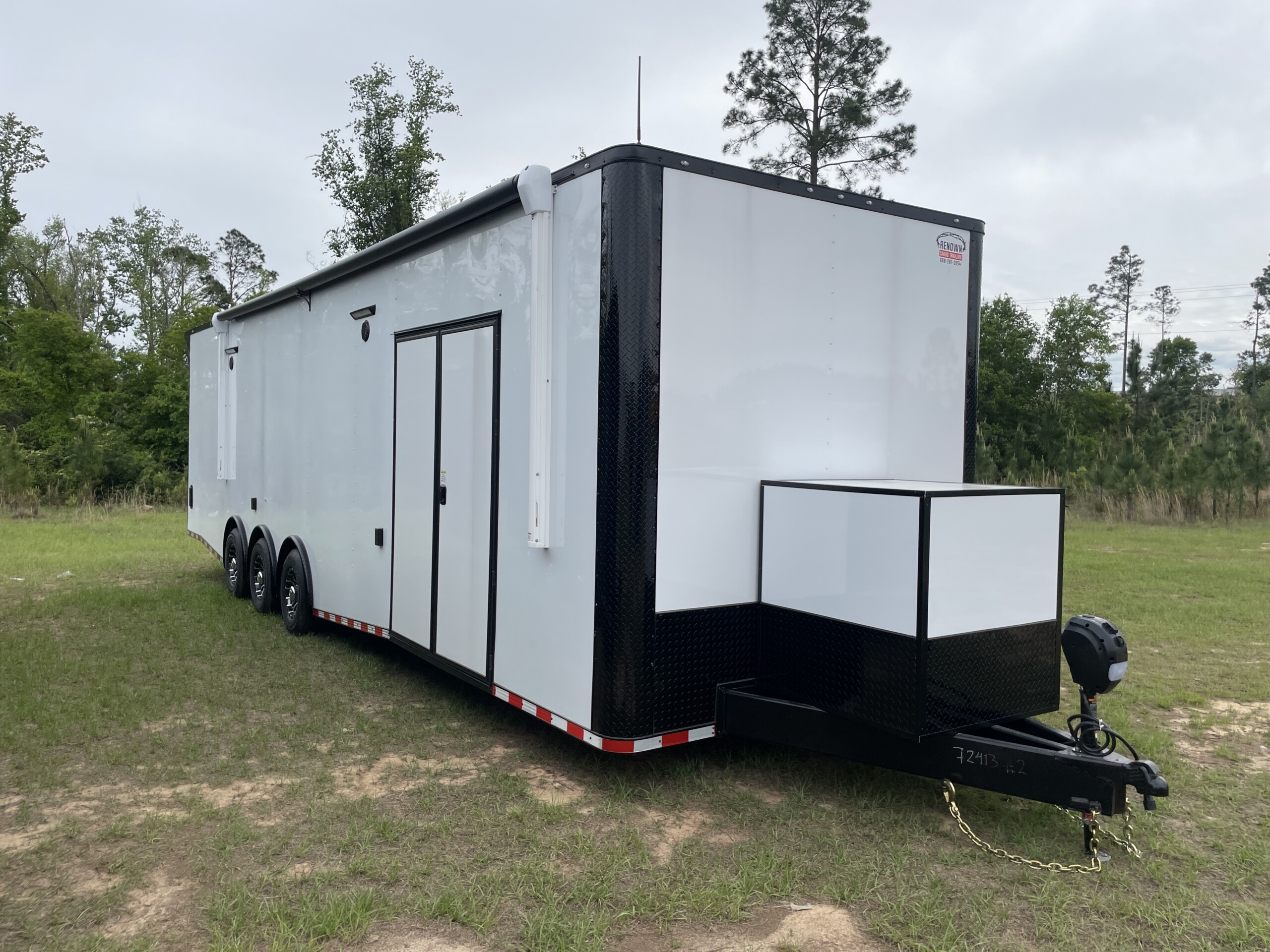 Rock Solid Cargo 8.5x34 triple axle race car trailer with white exterior, spread torsion axles, electric awning, generator compartment, RTP flooring, and premium race package.