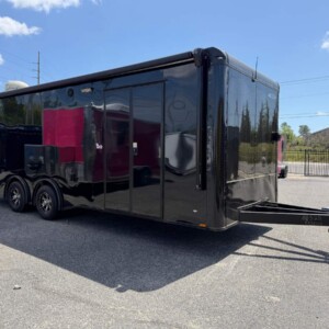 Freedom Cargo 8.5x24 race car trailer with black Polycore exterior, blackout package, spread torsion axles, electric awning, escape door, cabinets, and air conditioning.