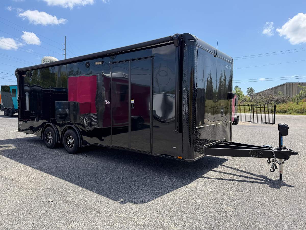 Freedom Cargo 8.5x24 race car trailer with black Polycore exterior, blackout package, spread torsion axles, electric awning, escape door, cabinets, and air conditioning.