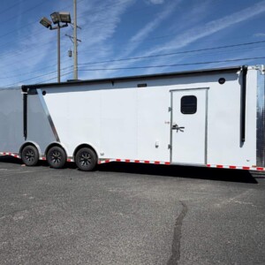 Freedom Cargo 8.5x34 triple axle race car trailer with full bathroom, white and gray Polycore exterior, electric awning, E-Track flooring, cabinets, and air conditioning.