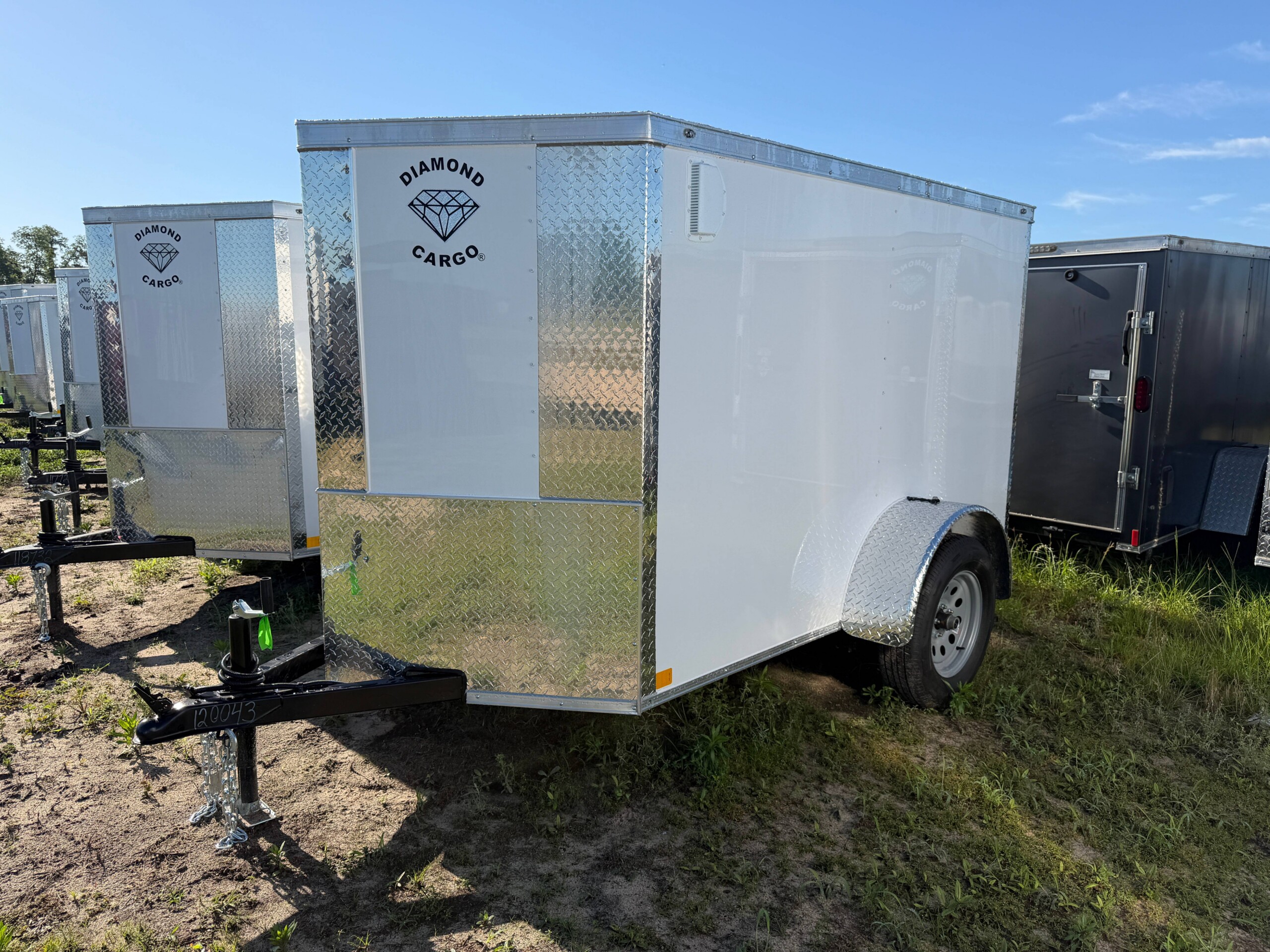 Diamond Cargo 5x8 enclosed cargo trailer with Polycore exterior, V-nose design, ramp door, LED lights, and silver modular wheels.