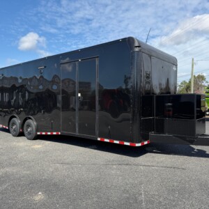 Rock Solid Cargo 8.5x28 blackout race car trailer with black poly exterior, spread torsion axles, escape door, generator compartment, and premium race package.
